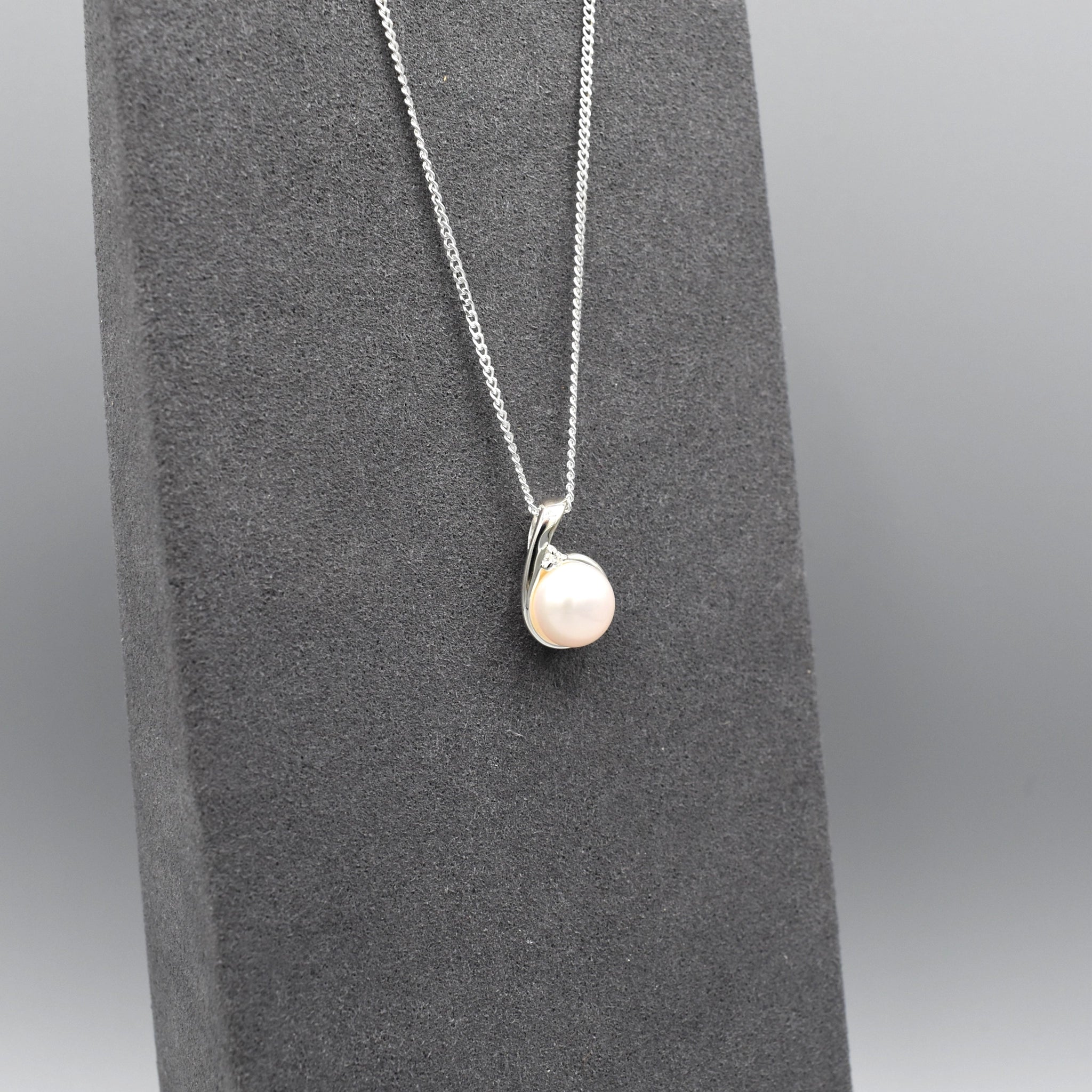 Small silver pendant with twist set with cubic zirconia stones and a round white fresh water pearl