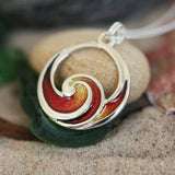 A silver pendant in the shape of an ocean wave coloured with red and yellow enamel lifestyle