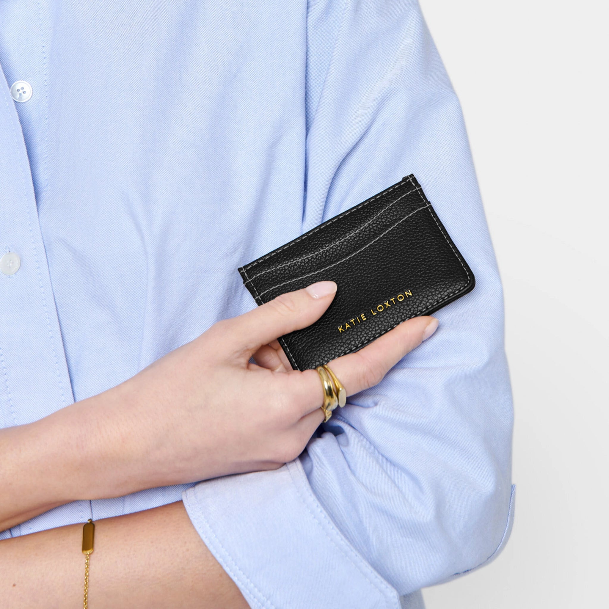 Model holding a faux black leather card holder with contrasting light stitching