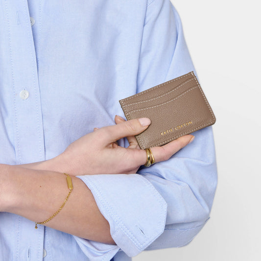 Model holding faux brown leather card holder with contrasting light stitching