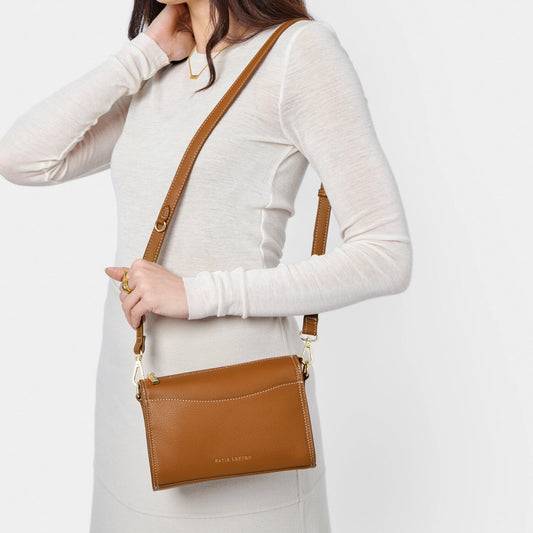 Model wearing a PU brown leather cross body bag with slip in front pocket and gold zip