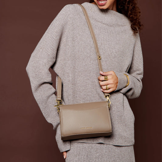 Model wearing a PU brown leather cross body bag with slip in front pocket and gold zip