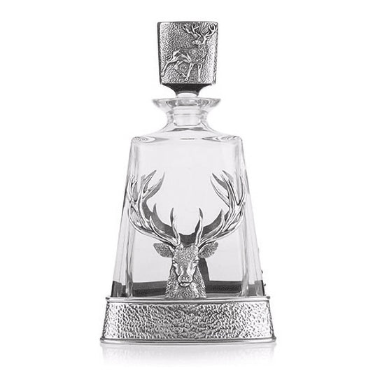A glass decanter with a pewter base featuring a large stag head and a stopper lid featuring a standing stag