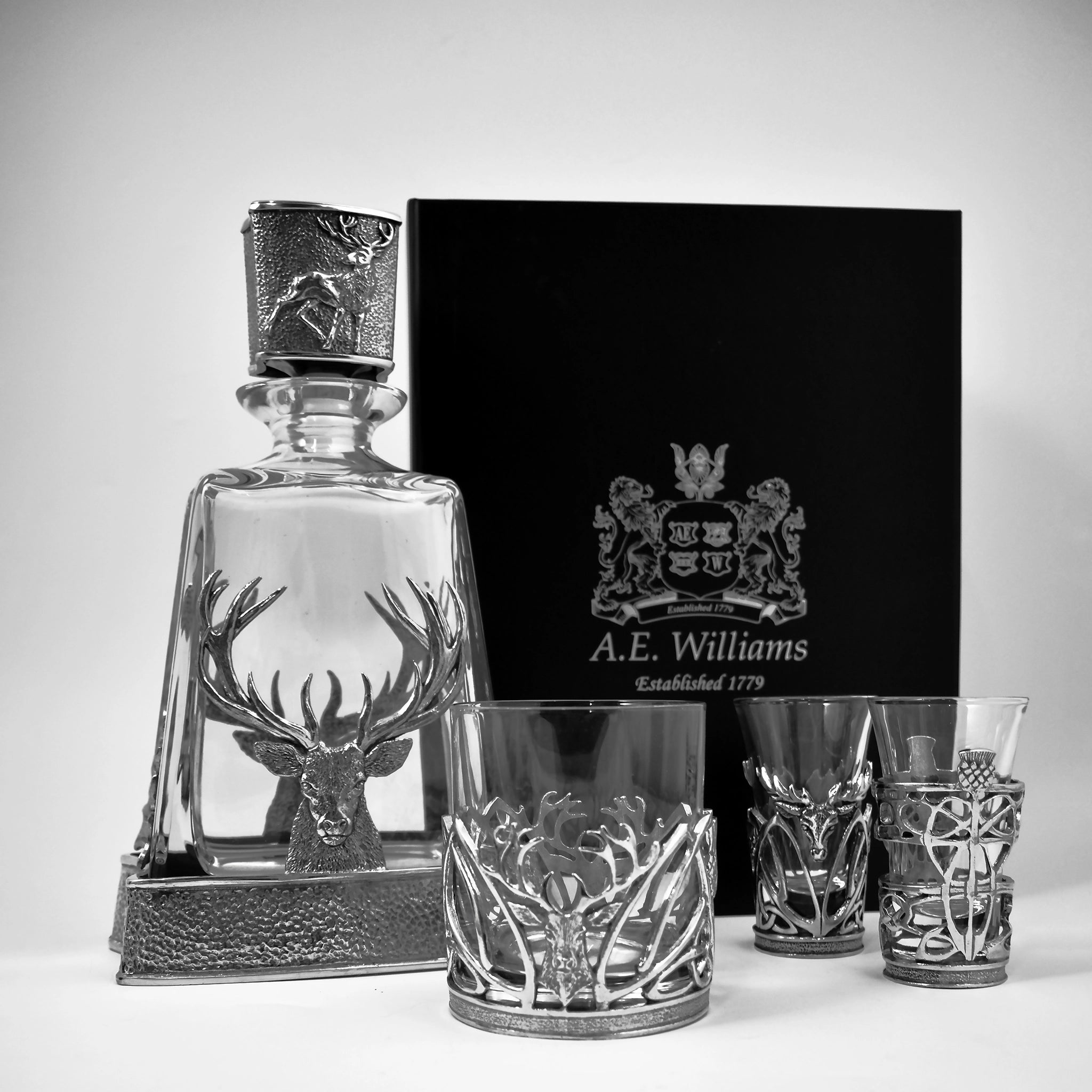 A glass decanter with a pewter stag design alongside matching tumbler and shot glasses