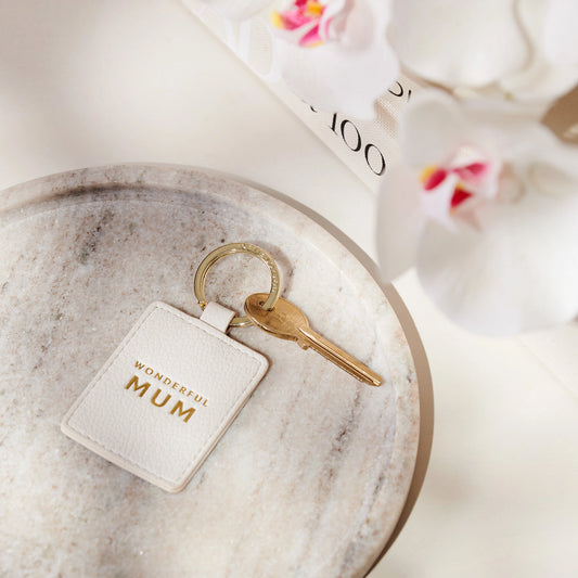 A faux leather off-white keyring featuring the words 'wonderful mum' in gold lettering with a key attached