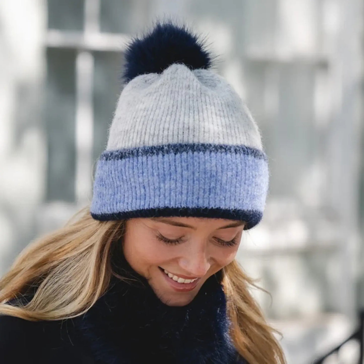 Model wearing two tone blue and beige bobble hat on model