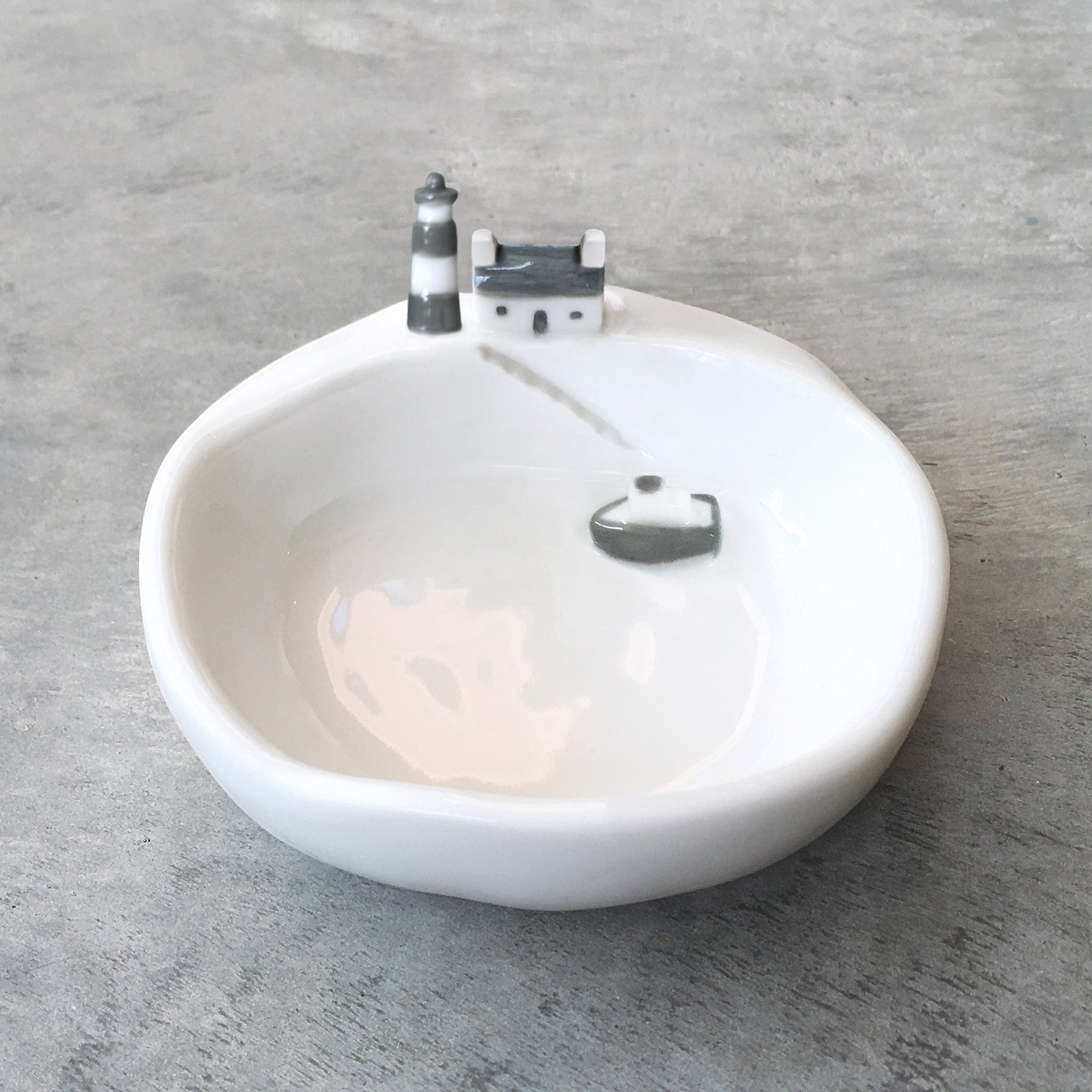 A white ceramic trinket dish bow with a boat and a lighthouse