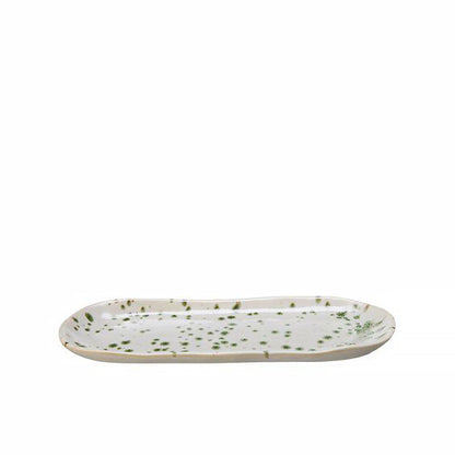 A long rounded plate in off-white with a green splatter pattern