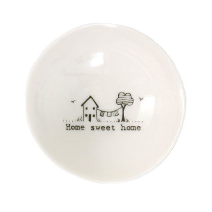 A white ceramic trinket bowl featuring a house & tree illustration and a quote