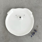 A round white ceramic trinket dish with a dog face and ears