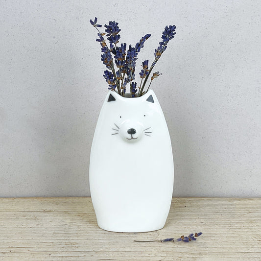 A minimalist white vase shaped like a cat with some lavender sprigs