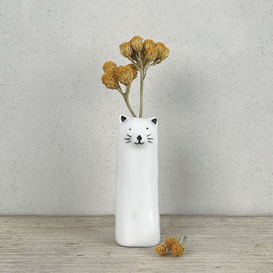 A slim modern minimalist vase shaped like a cat holding dried flowers