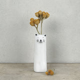 A slim modern minimalist vase shaped like a cat holding dried flowers