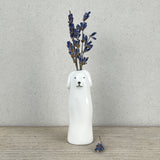 A slim modern minimalist vase shaped like a dog holding dried lavender