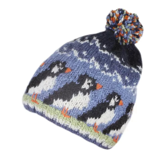 A knitted hat with colourful pompom featuring a design of a row of puffin birds in blue