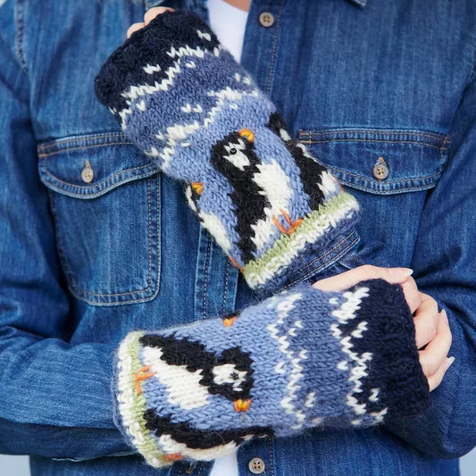 Model wearing a pair of knitted hand warmers featuring rows of puffins with beaded eyes