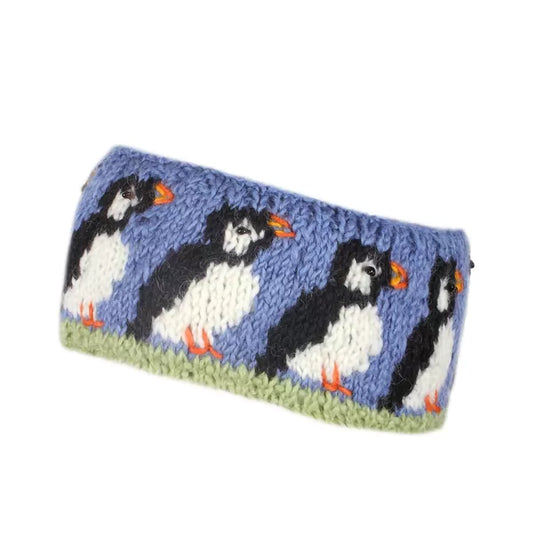 A knitted headband in blue featuring a design of a row of Puffins with beaded eyes