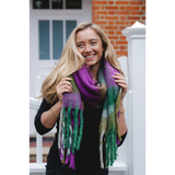 Model wearing a chunky knit purple, blue and green check patterned scarf with tassel trim