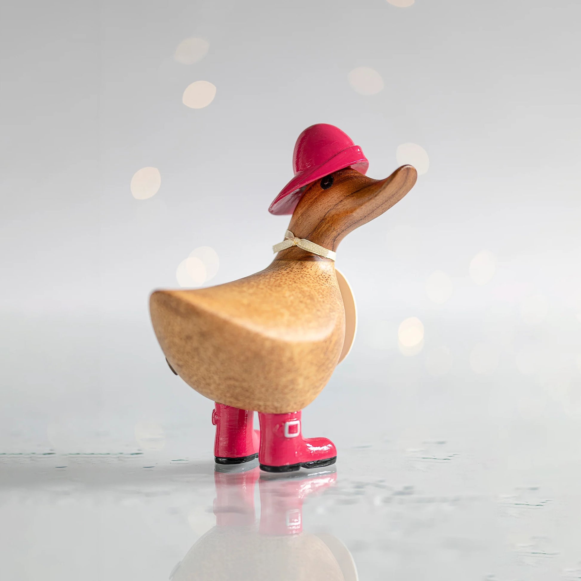 Wooden duck collectible figure in pink rain hat and boots