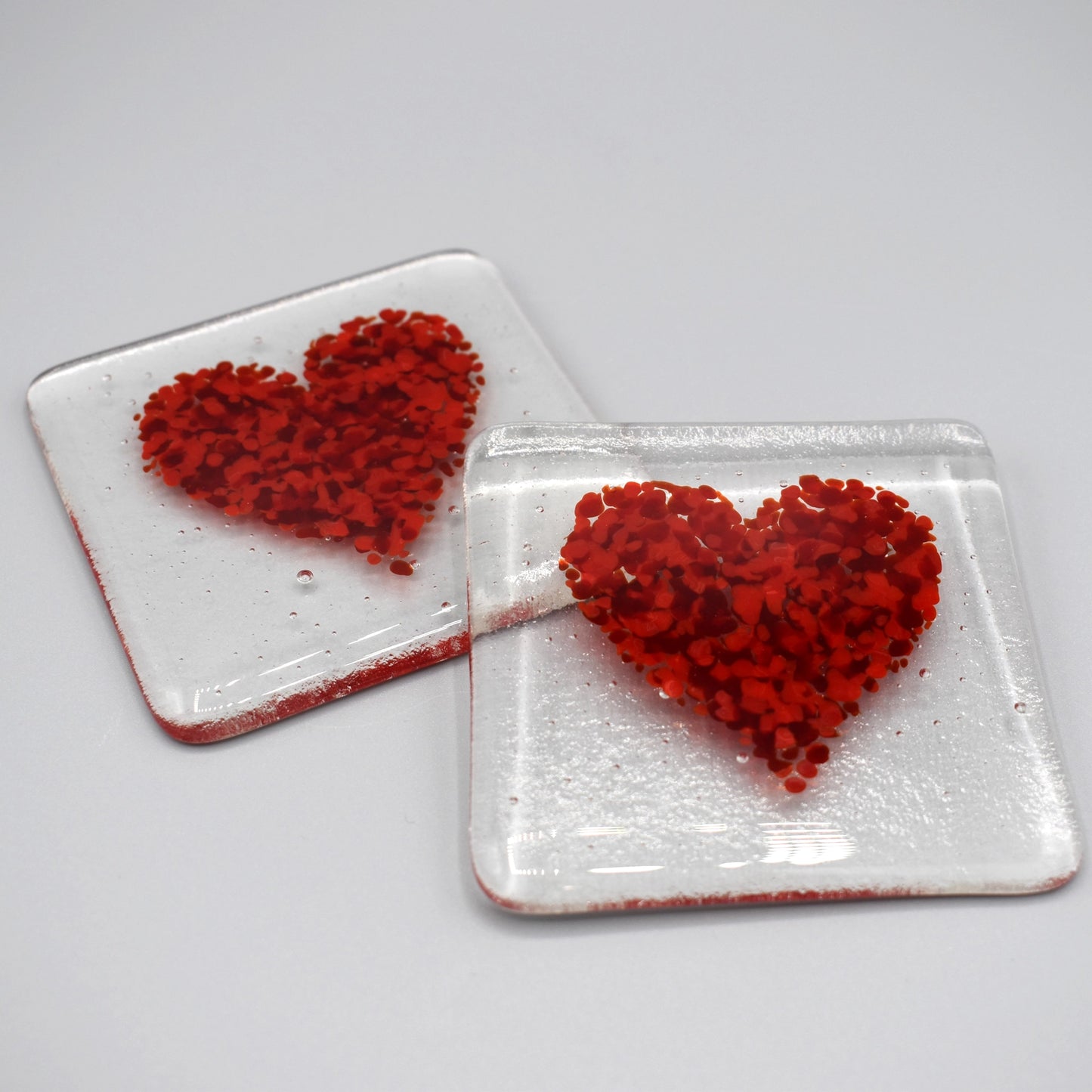 Clear glass square coasters with red hearts design