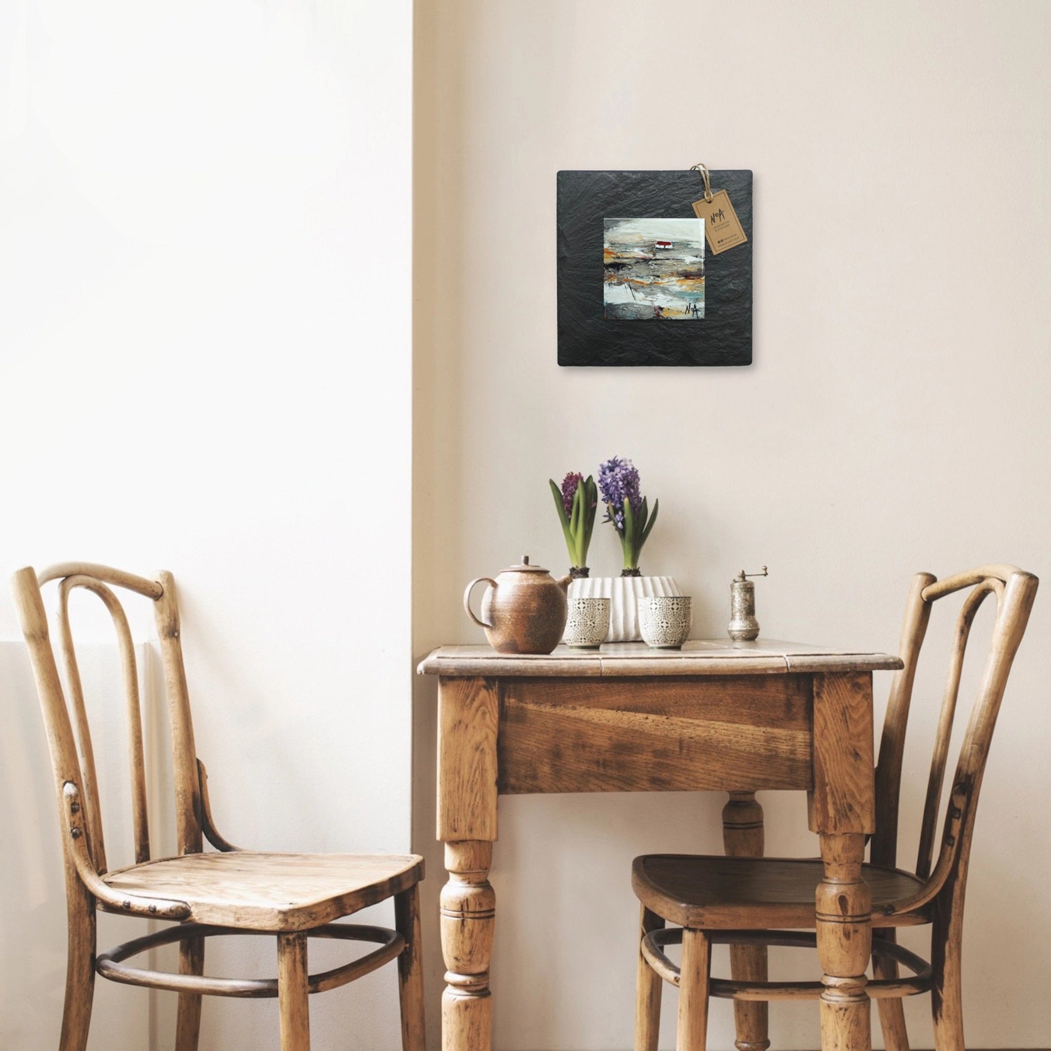 A tile mounted on slate featuring a textured painting of a bothie in the Highlands hanging