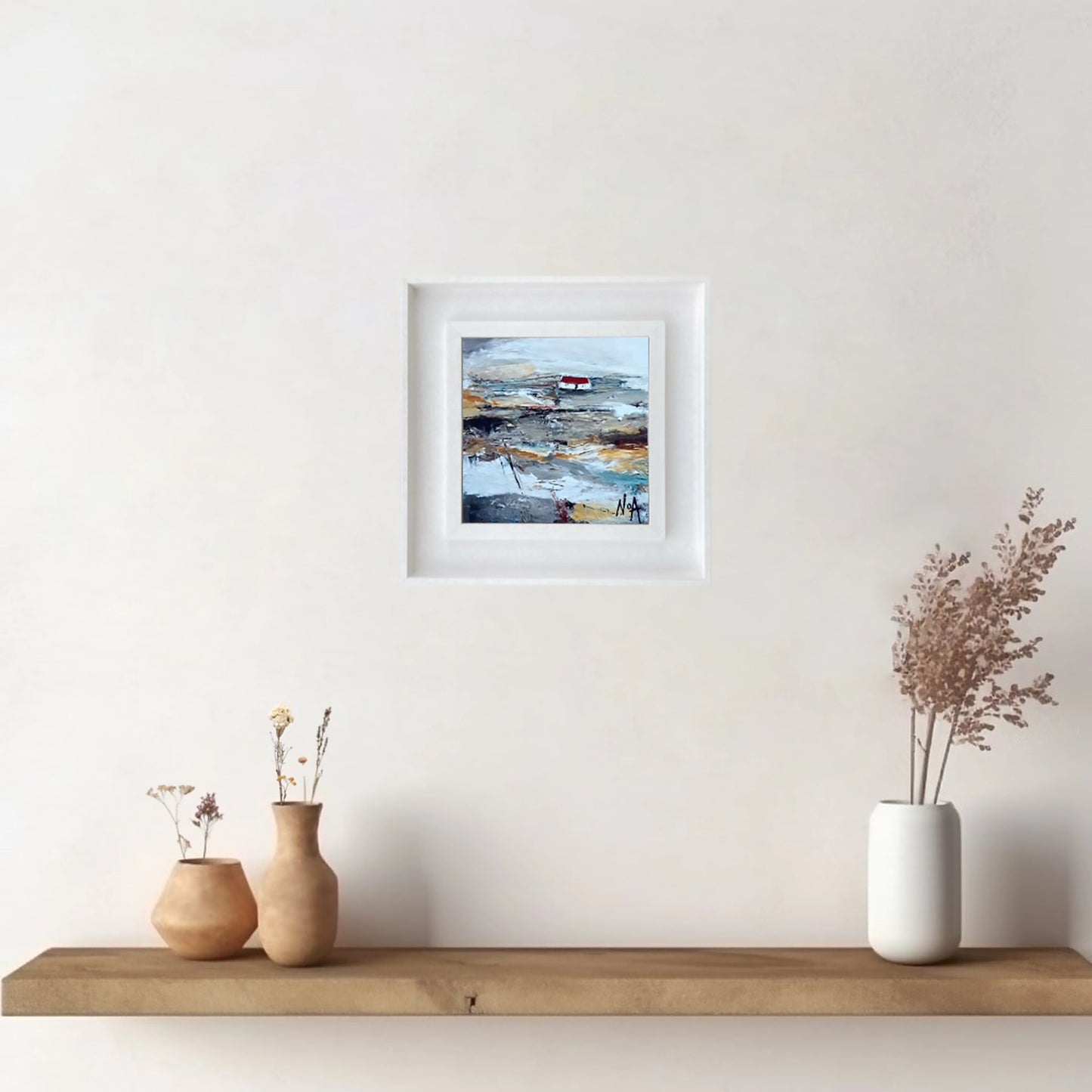 A ceramic tile printed with an abstract painting of a cottage mounted on a white frame hanging on wall