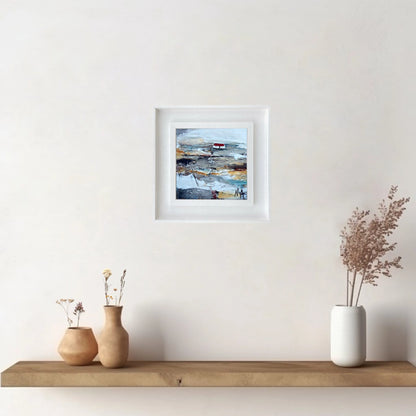 A ceramic tile printed with an abstract painting of a cottage mounted on a white frame hanging on wall