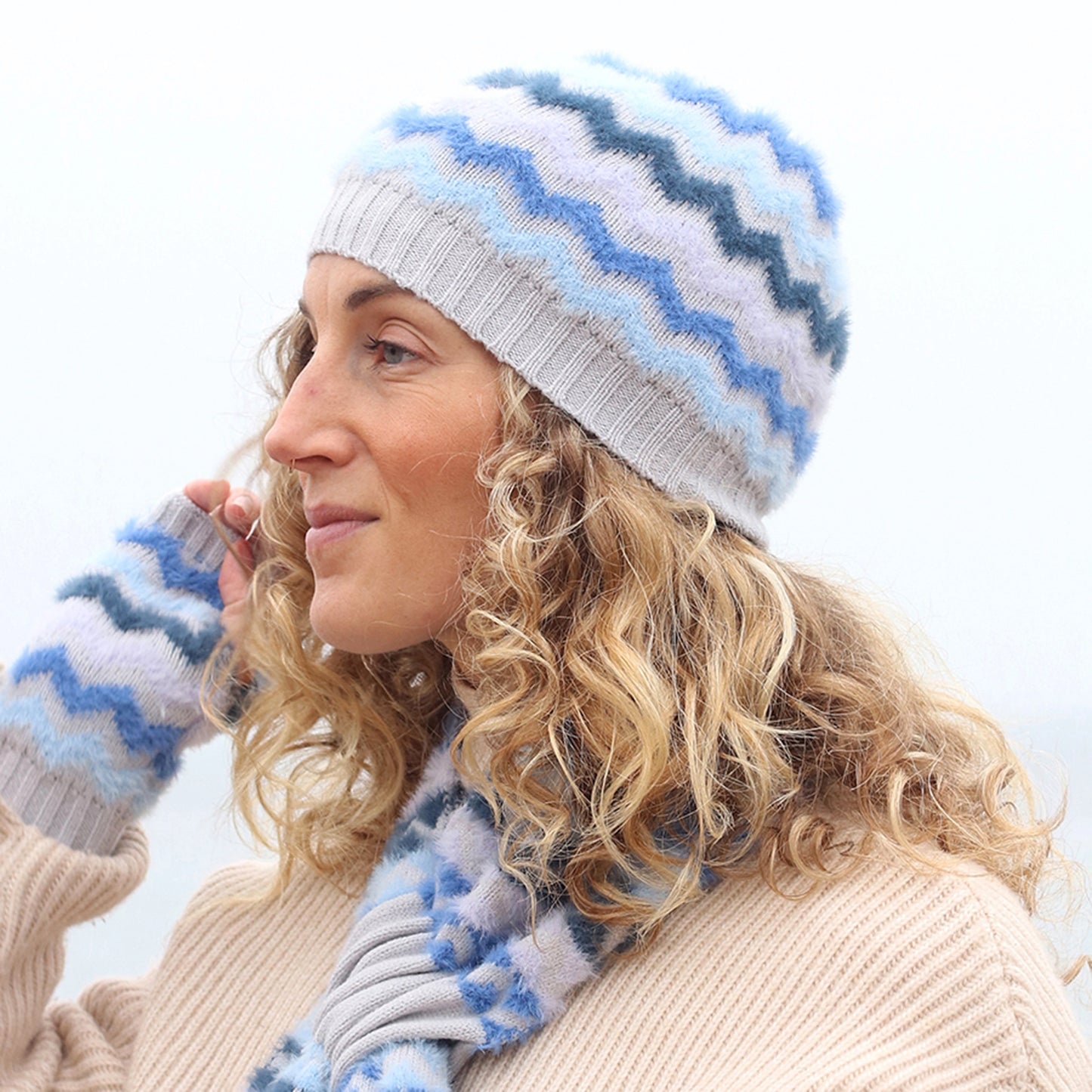 Model wearing grey knitted beanie hat with brush chevron stripes in different shades of blue