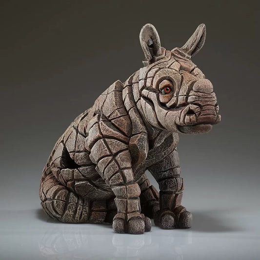A textured and painted sitting rhino calf figure sculpture