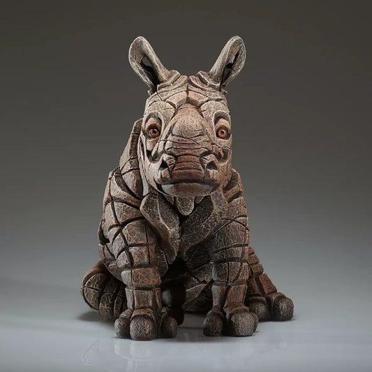 A textured and painted sitting rhino calf figure sculpture front view