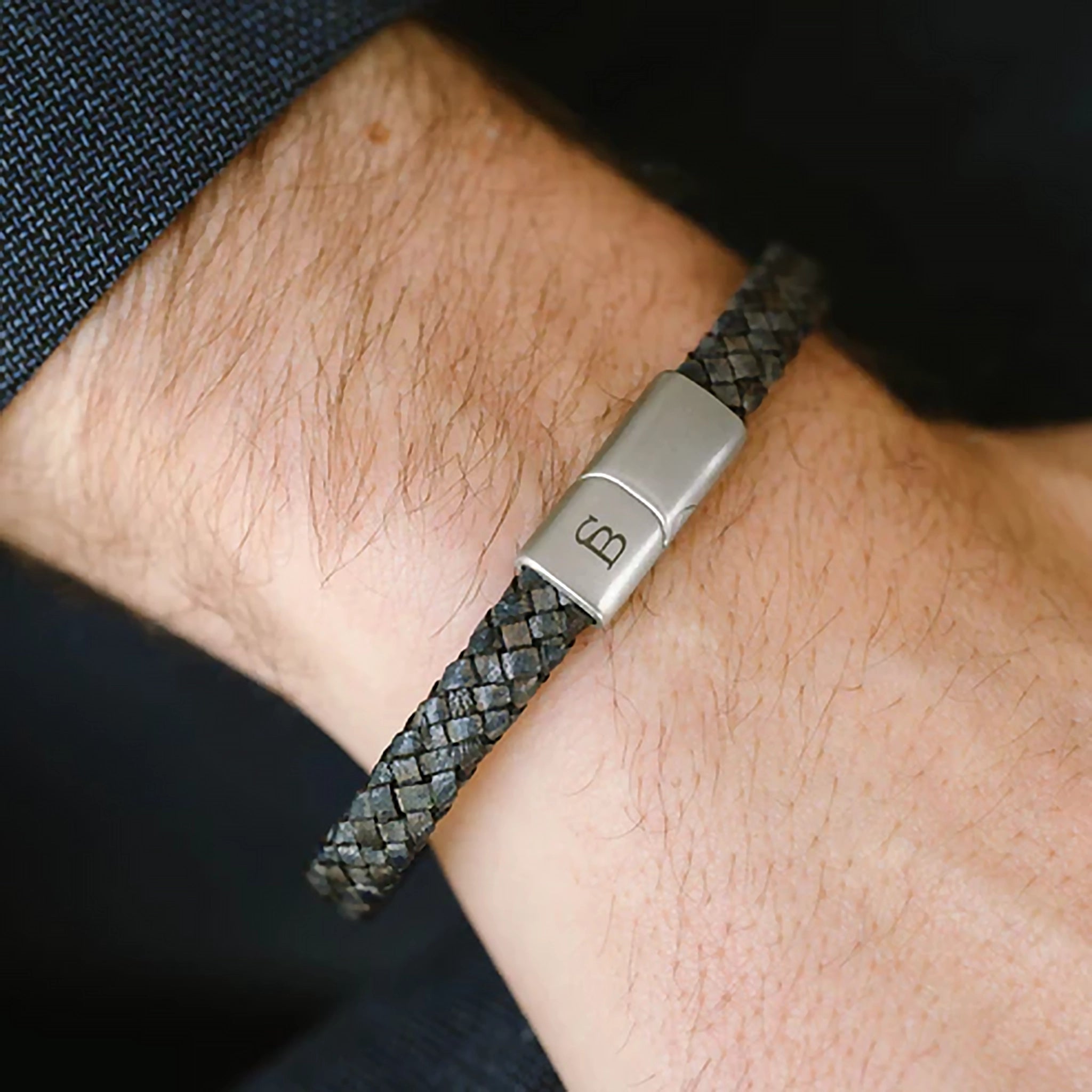 Model wearing a braided band blue leather bracelet with monogramed stainless steel clasp