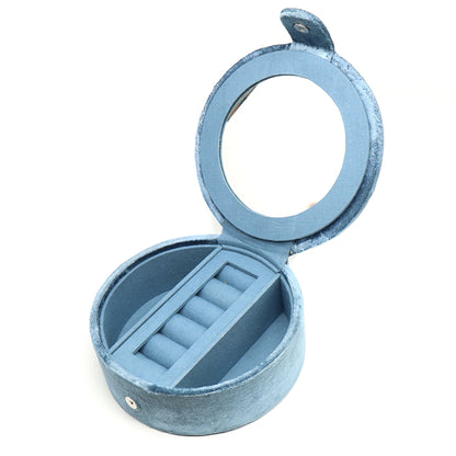 A round dusky blue velvet jewellery box with two open compartments and a ring roll