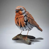 A textured and painted robin on a branch figure sculpture