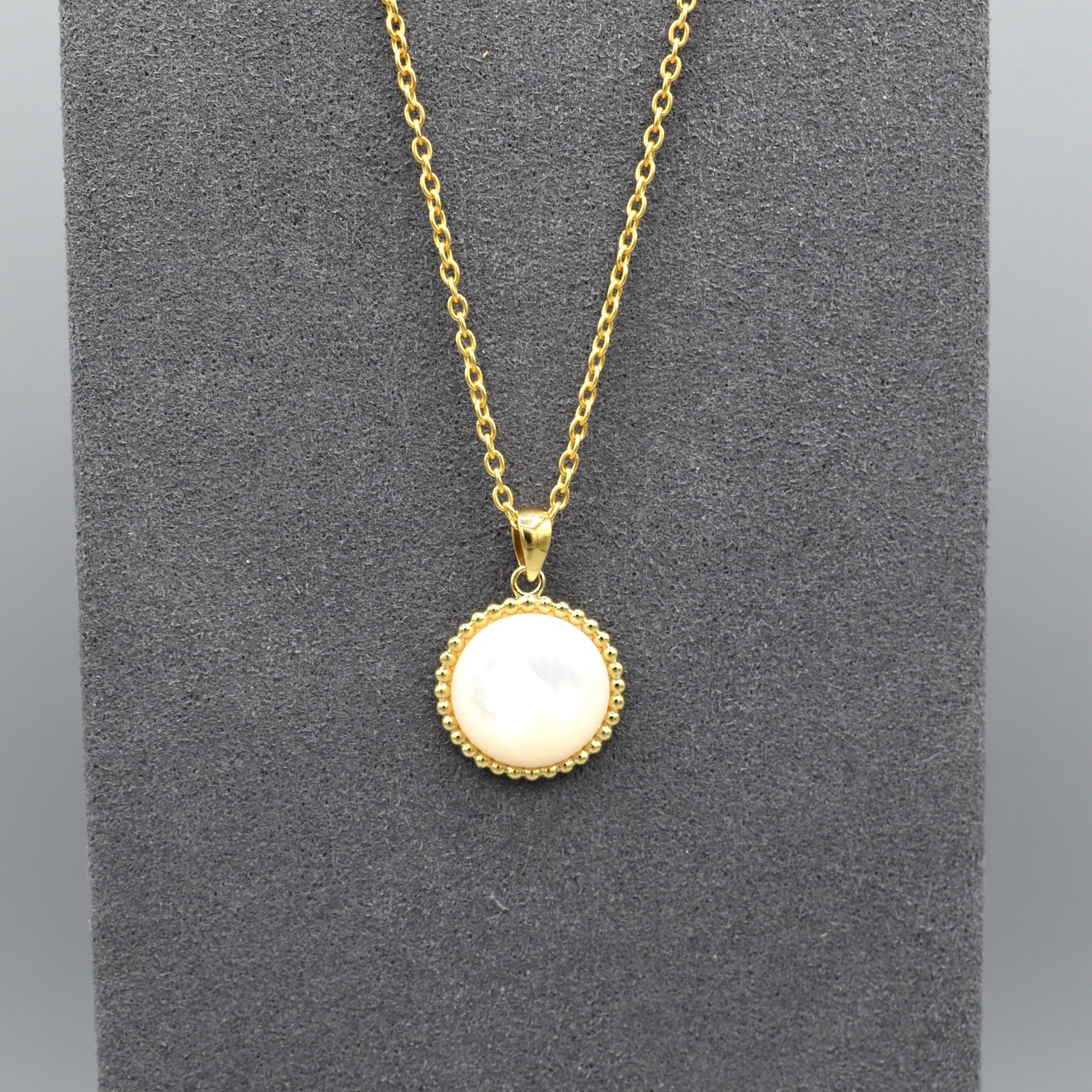 Pendant with round popcorn frame in yellow gold plating with a large round mother of pearl stone in the centre