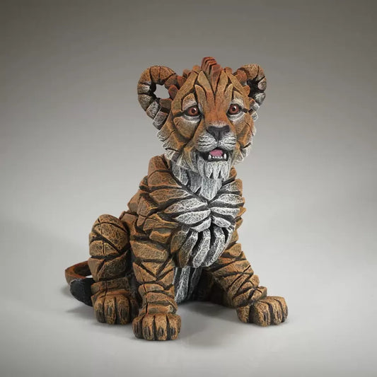 A textured and painted sitting lion cub figure sculpture