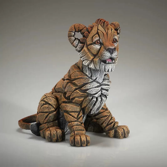 A textured and painted sitting lion cub figure sculpture side view