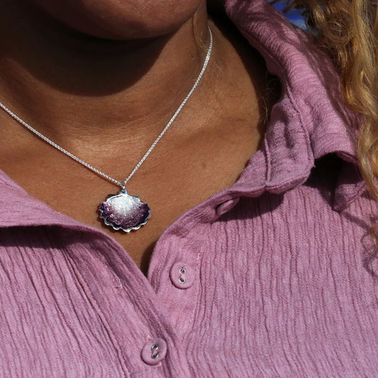 Model wearing silver scalloped shaped pendant with pink enamel