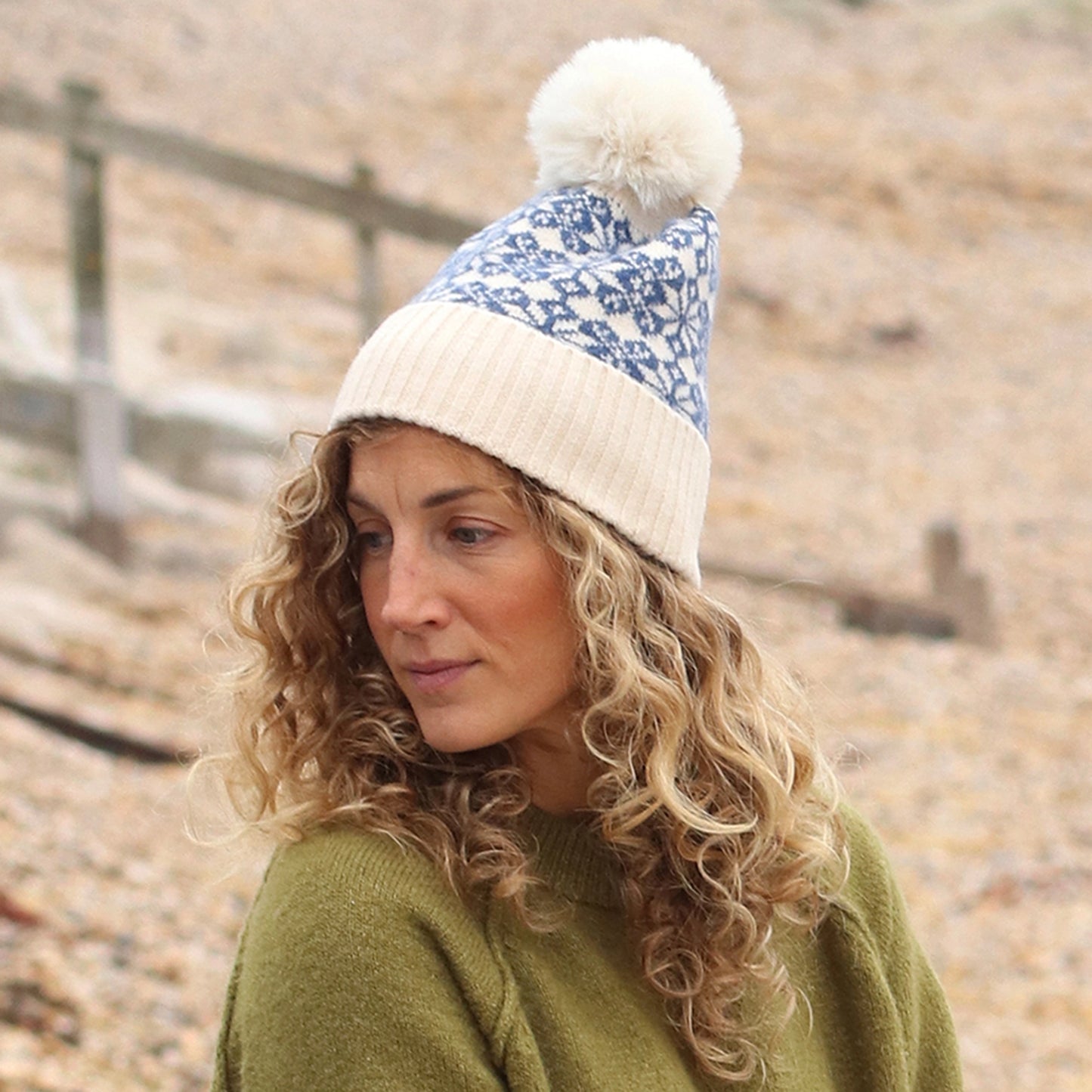 Mode wearing a Scandi style star patterned faux fur pompom hat in blue and cream