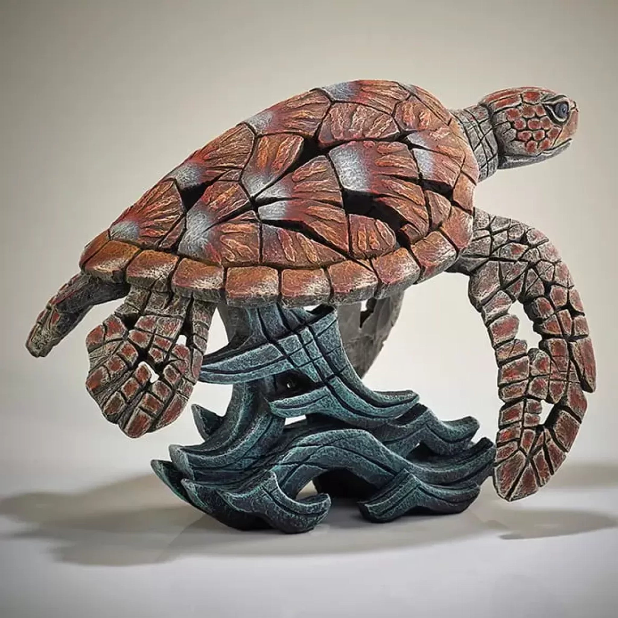 A textured and painted sea turtle surfing waves sculpture from back