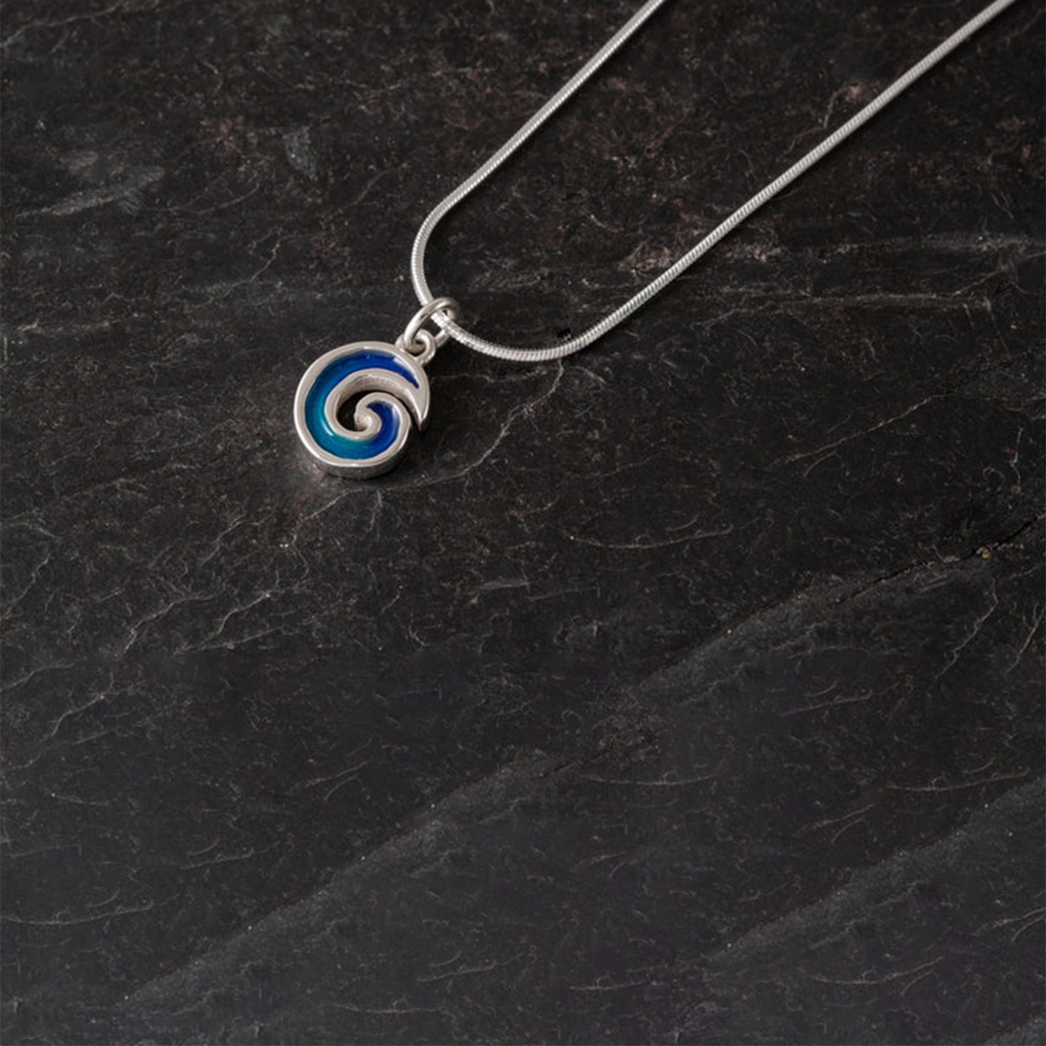A round wave shaped pendant with vibrant blue enamelling