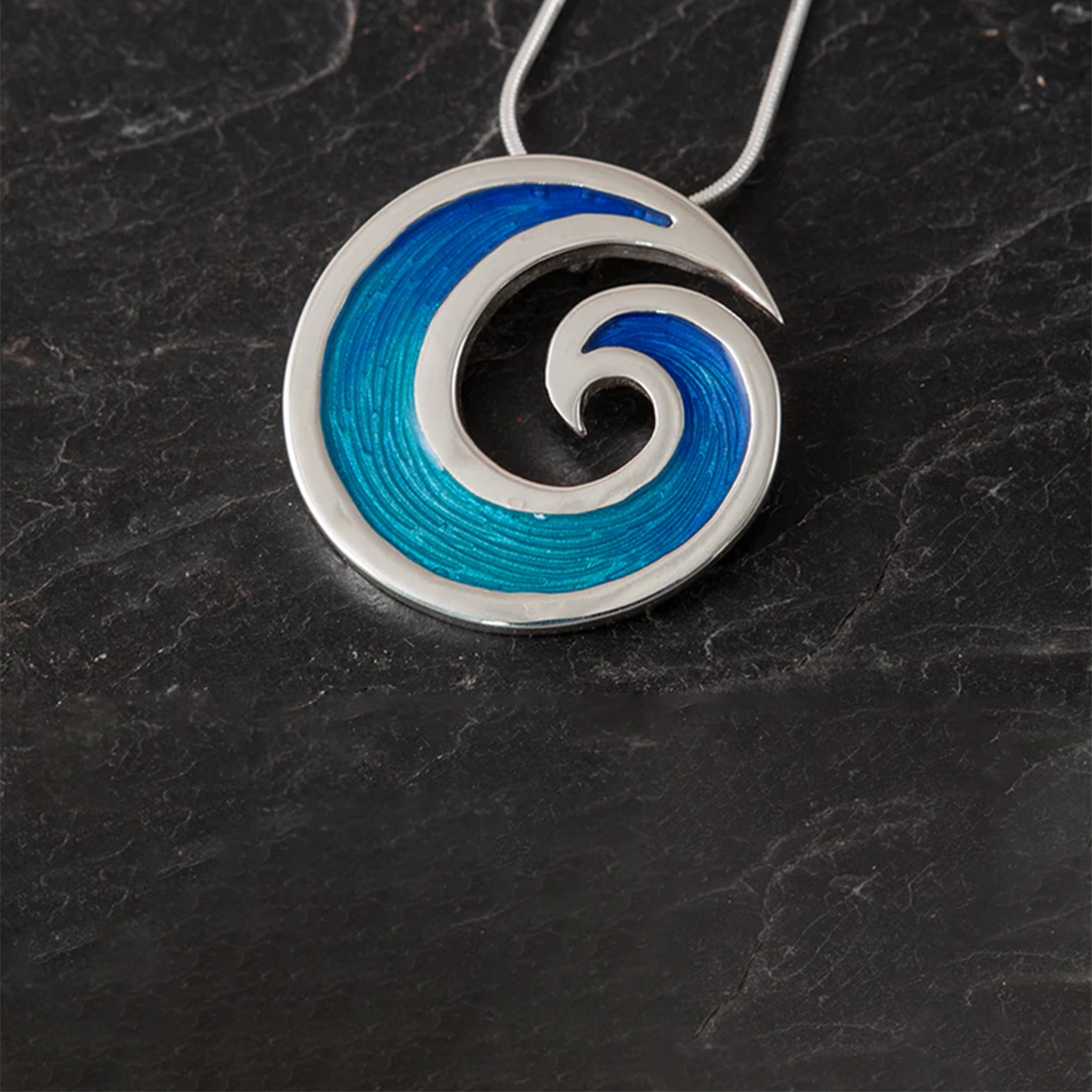 A round wave shaped pendant with vibrant blue enamelling