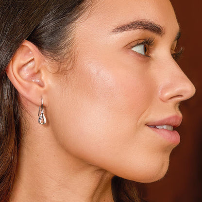 Model wearing a pair of silver ribbon twist loop drop earrings