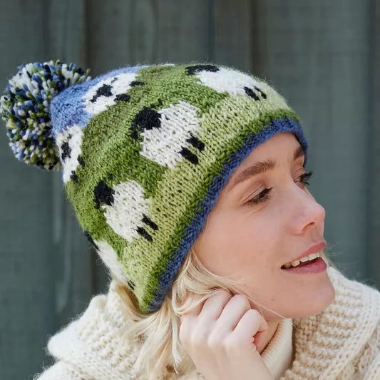 Model wearing a knitted beanie hat with sheep design and a pompom