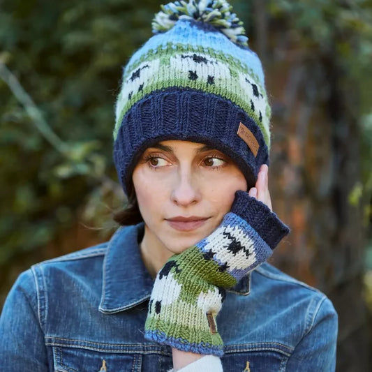 A pair of knitted handwarmers in blue and green, featuring two rows of white sheep on model