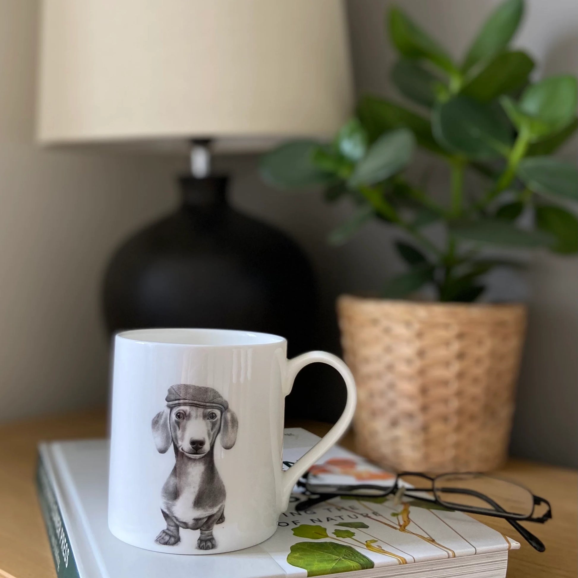 White mug with grey illustration of a sausage dog in a beret hat - lifestyle