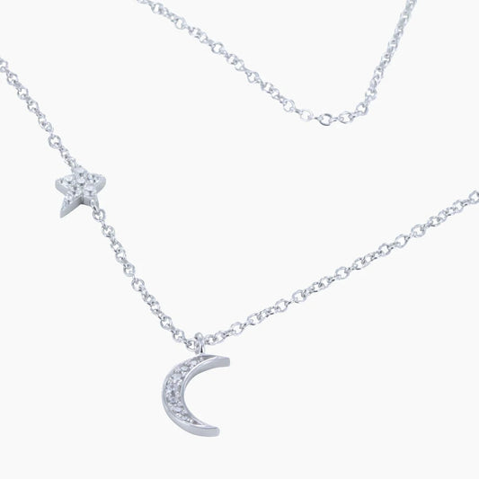 A silver necklace featuring a moon and star set with cubic zirconia stones