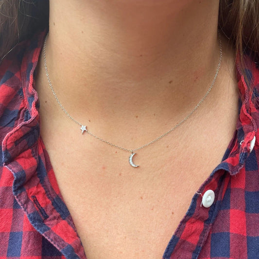 Model wearing a silver necklace featuring a moon and star set with cubic zirconia stones