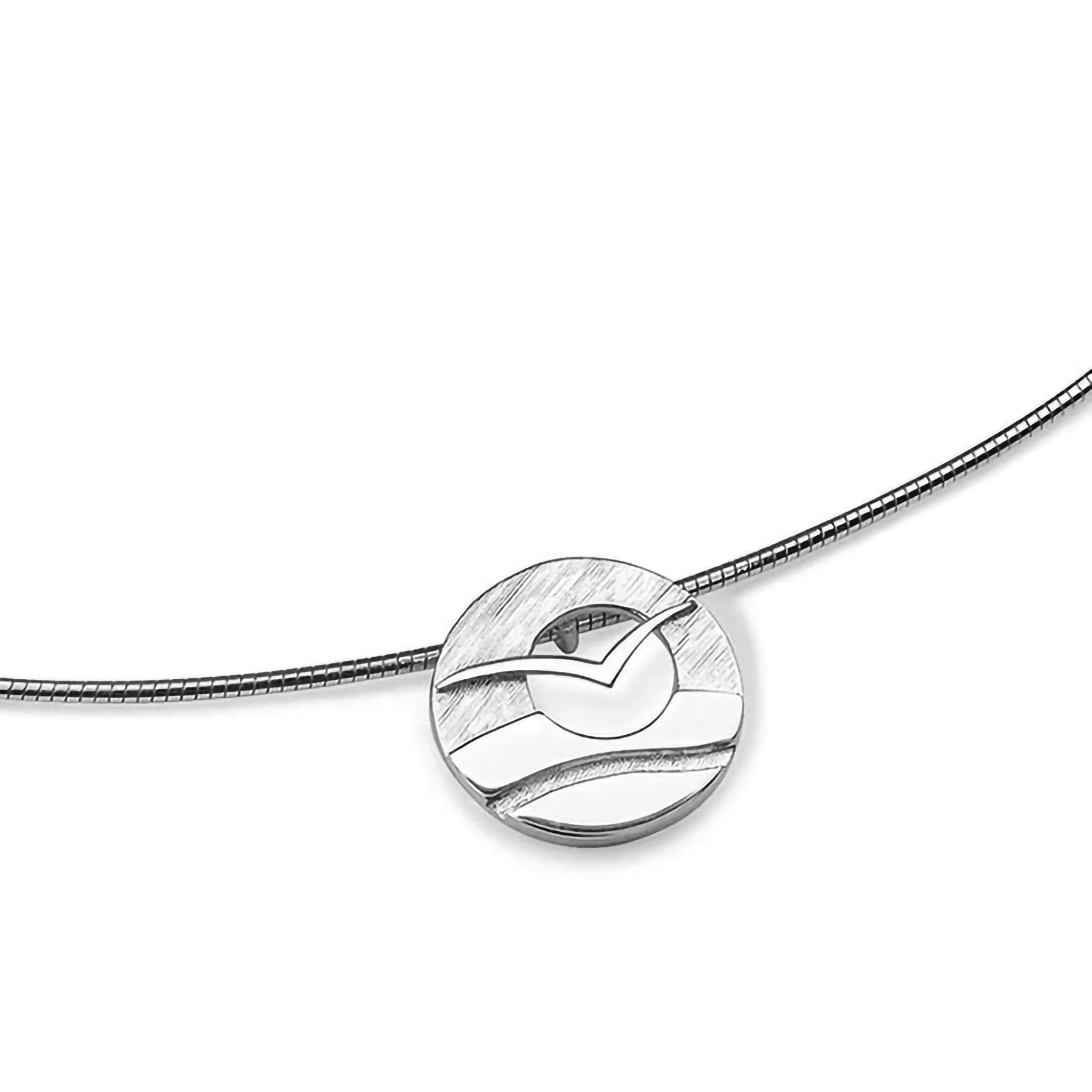 A silver wire necklet with small pendant featuring a flying sea bird in front of a cutout sun over water