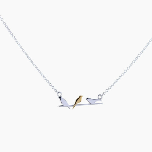 A necklace featuring three birds on a branch in silver, the centre one in gold