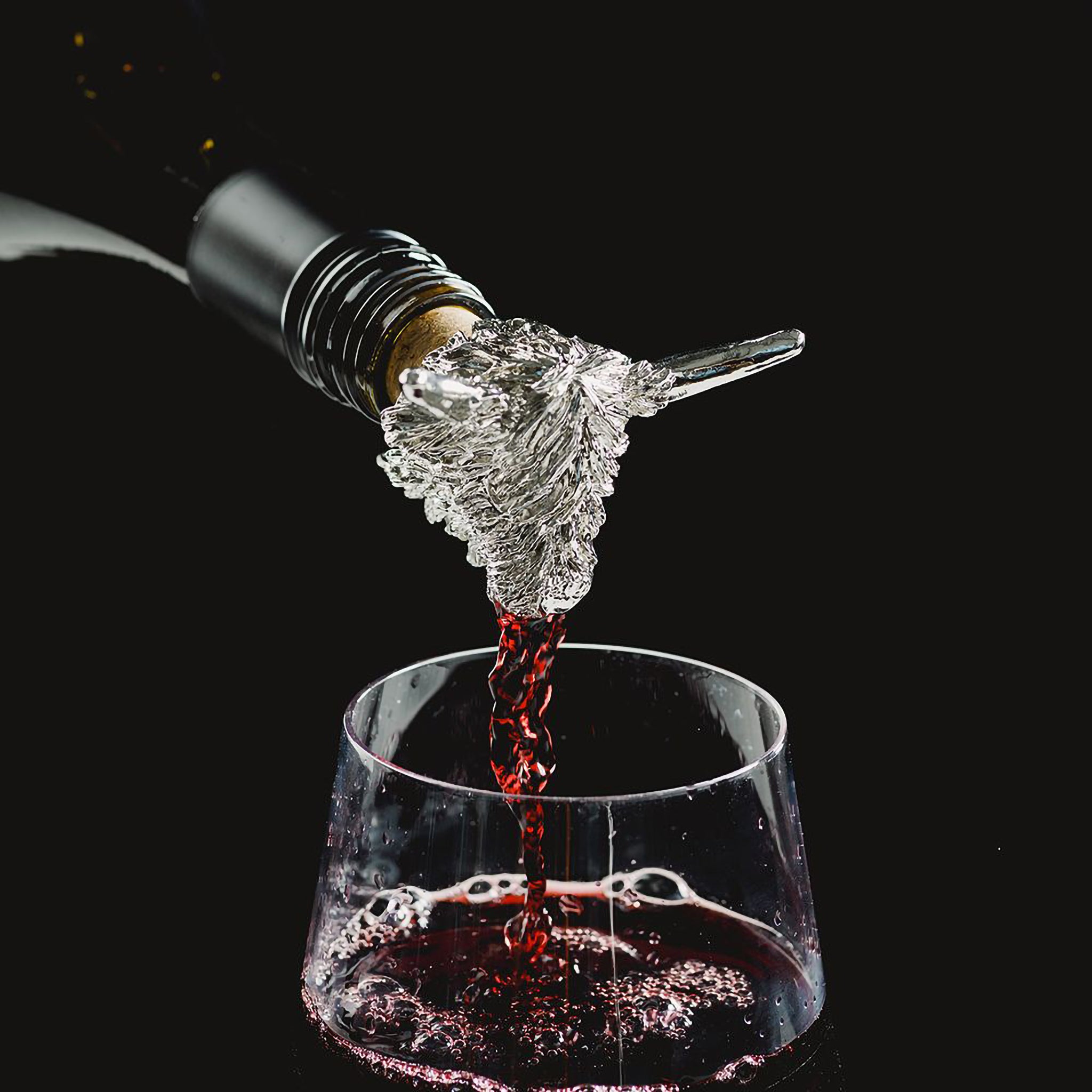 A wine pourer with silver Highland cow head pouring red wine